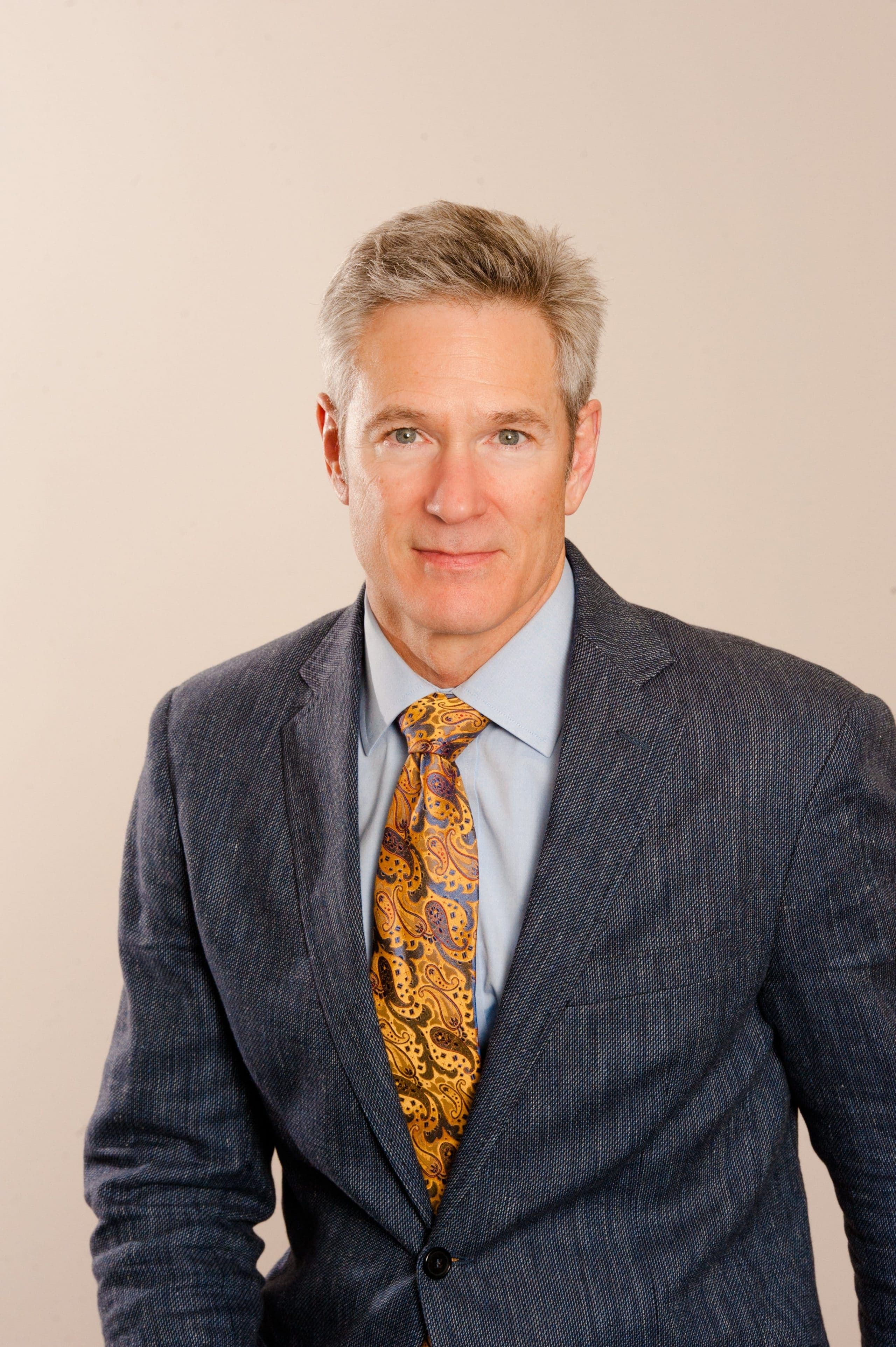 Dr. Richard Grimsley in a jacket and tie, photographed against a plain backdrop